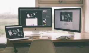 Espacio de trabajo con laptop y monitores mostrando un proyecto de diseño web
