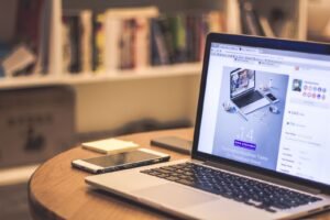 Espacio de trabajo con laptop mostrando un sitio web, smartphone y libros